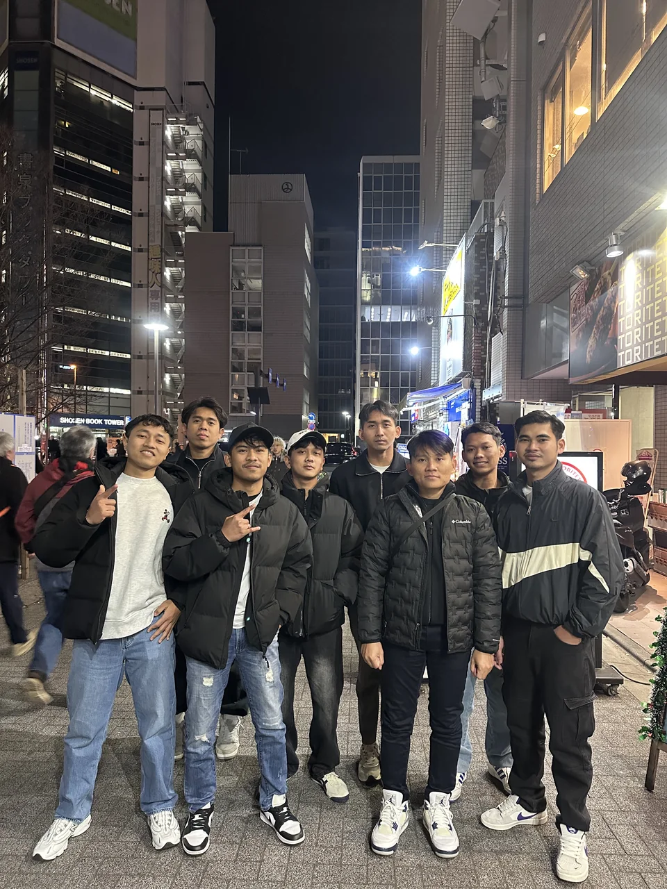 Delapan orang berfoto bersama di jalanan Jepang pada malam hari