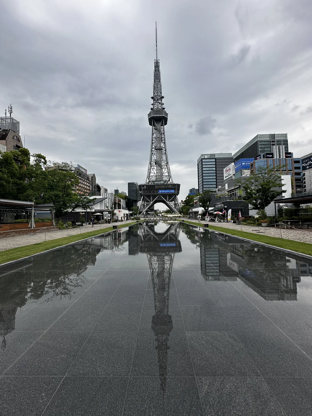 Menara kota dan bangunan di sekitarnya terpantul pada kolam panjang