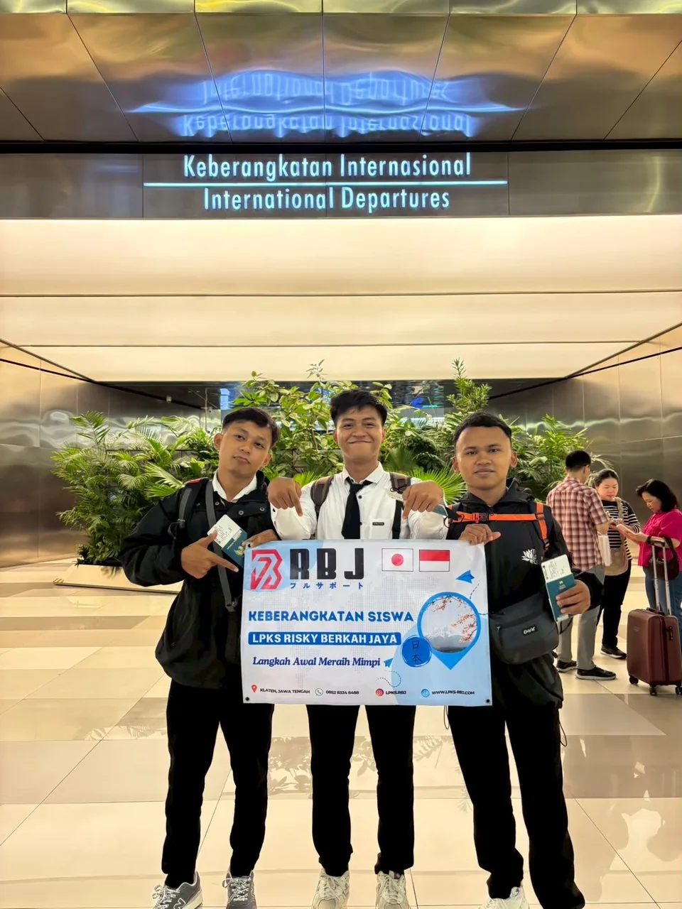 Tiga siswa membawa spanduk RBJ di area keberangkatan internasional