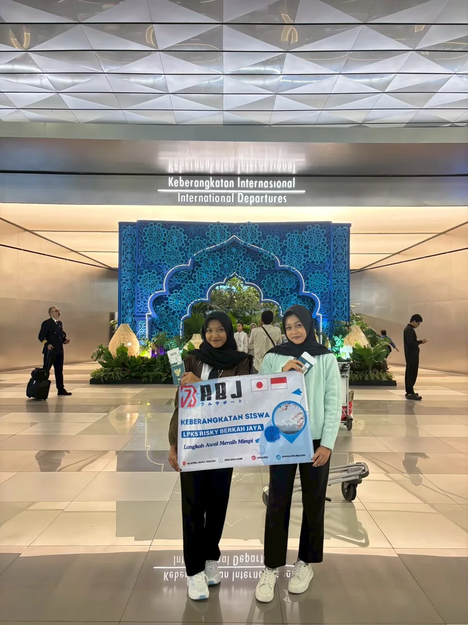 Dua siswi berfoto bersama dengan spanduk keberangkatan RBJ di bandara